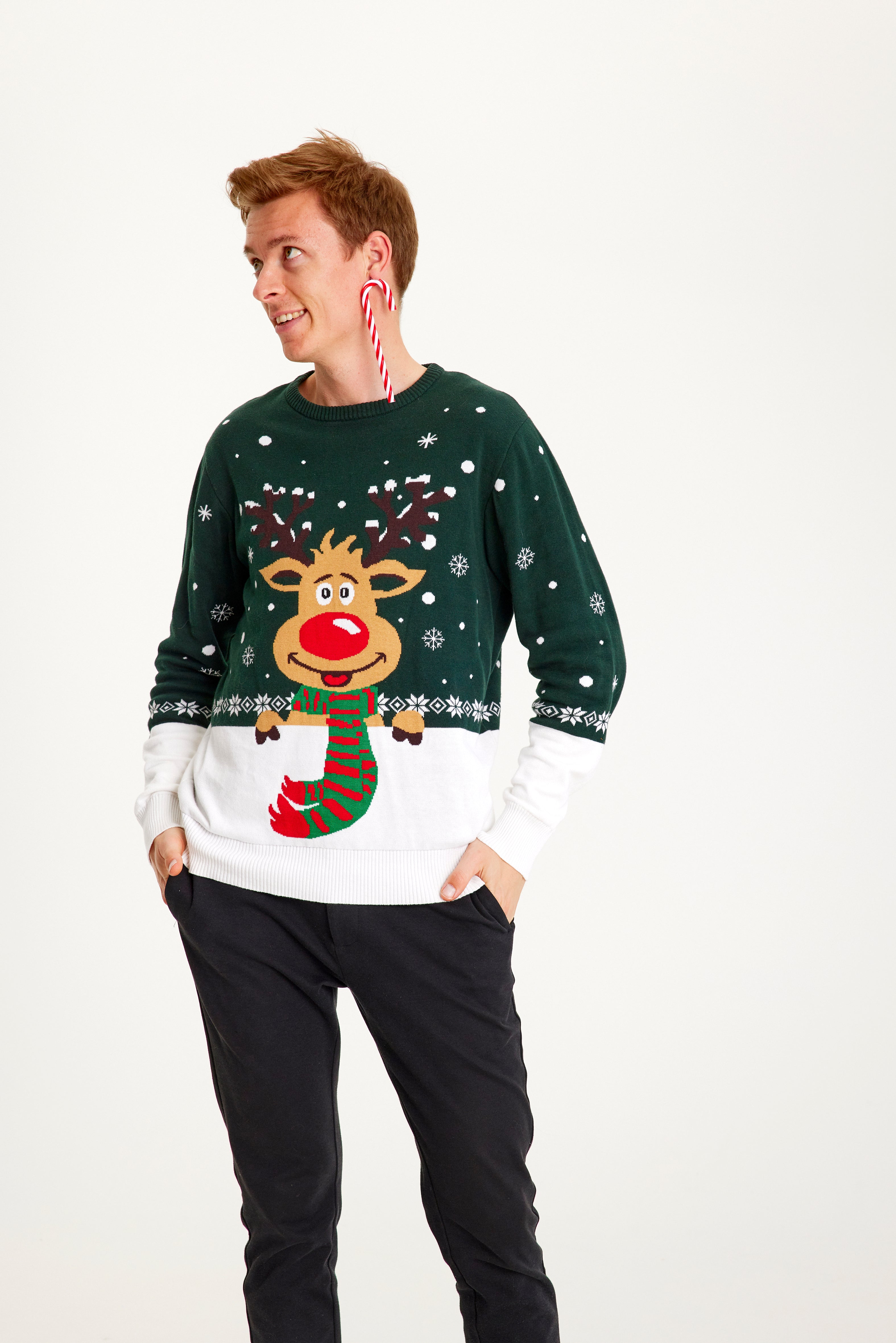 En mand med en sukkerstok i øret kigger til siden, mens han er iført en grøn julesweater.